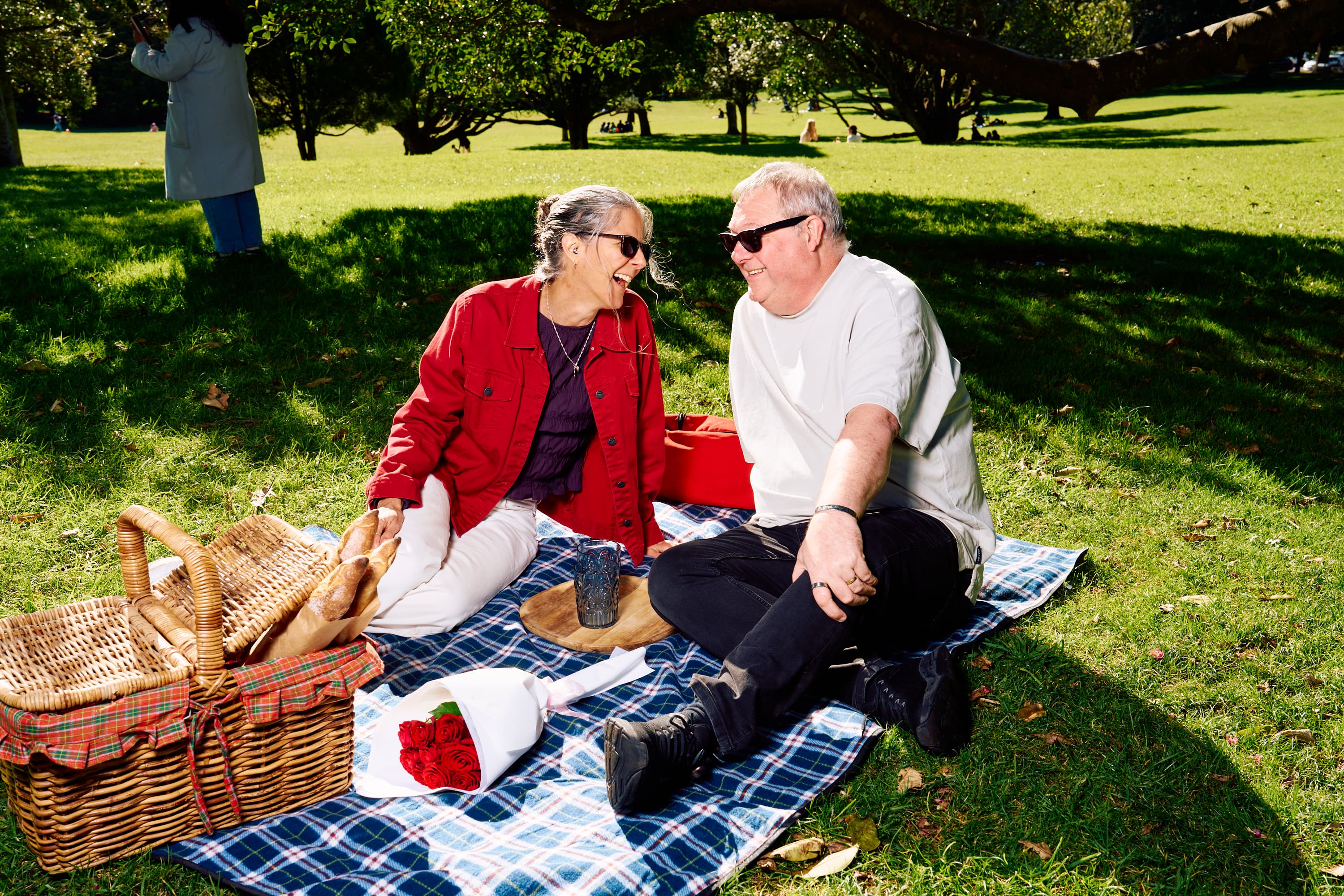 Couple having a picnic and looking each other with sunglasses on